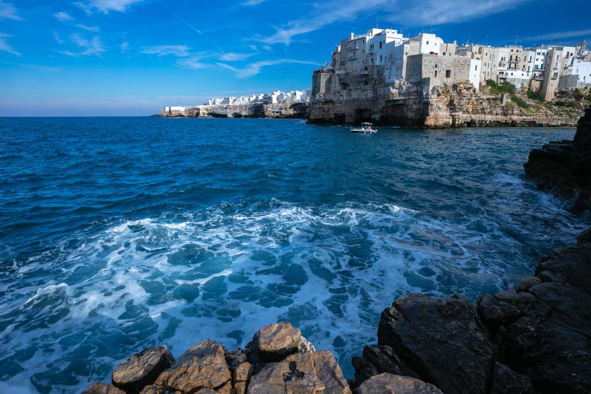 Interni di un parco giochi moderno a Polignano a Mare, bambini di diverse età che si divertono su scivoli colorati e altalene, genitori rilassati nelle vicinanze